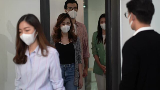 Group of professional asian business and using infrared thermometer for checking body temperature staff fever before work in quarantine for coronavirus wearing protective mask at office	