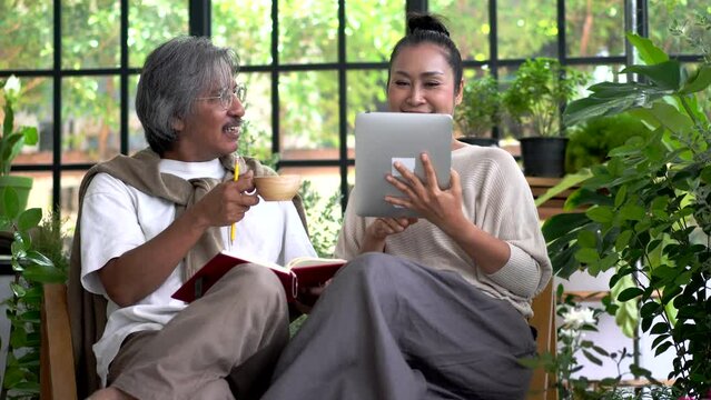 Senior couple asian family having good time using tablet computer together.Happy elderly husband and wife checking social media and reading news or shopping online while sitting at home	