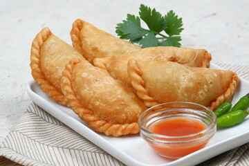 Curry puff or Pastel Goreng is Pastry Popular in Indonesia.
fried pastry with filling of sautéed vegetable , chicken and boiled egg. accompanied with  sauce or raw chilli pepper - obrazy, fototapety, plakaty