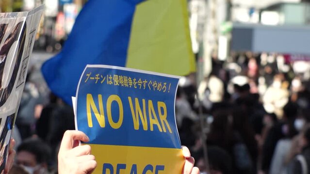 SHIBUYA, TOKYO, JAPAN - 26 FEB 2022 : Many Ukrainians and Russians living in Japan gathered in front of Shibuya station to protest Russia's invasion of Ukraine. Slow motion shot. - Powered by Adobe