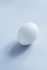 White egg on a blue background. Raw chicken egg close up. Minimal Easter concept