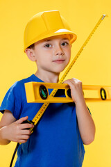 The preschooler in a helmet with a construction level plays a builder