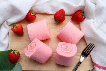 Pink Strawberry roll cake with cream served on wood tray at top view 