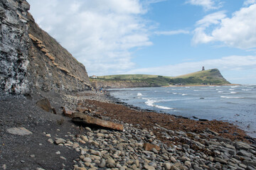 The rocky beach at Kimmeridge Bay in Dorset, UK, with Clavell Tower in surrounding cliffs