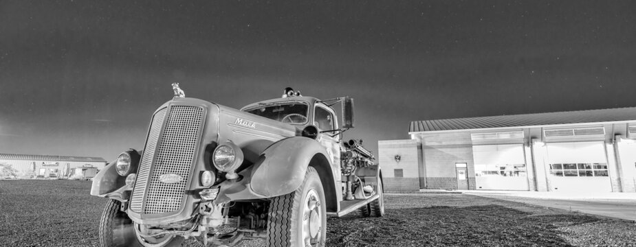 PAGE, AZ - JUNE 27, 2018: Old vintage rusty car in fornt of Page United Firefighters Department at night.