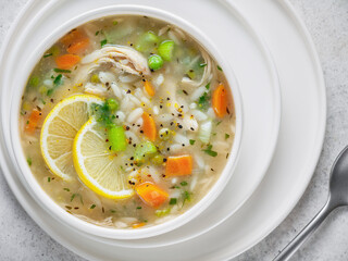 Bowl of Italian lemon chicken orzo soup. Flat lay, close-up. From above. Horizontal