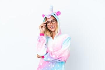 Blonde Uruguayan girl wearing a unicorn pajama isolated on white background with glasses and happy