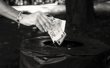 Woman throws away money banknotes, lots of euros thrown in the public trashbin