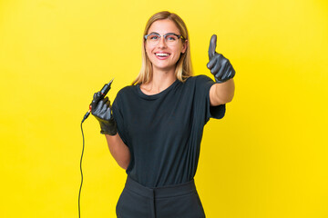 Tattoo artist Uruguayan woman isolated on yellow background with thumbs up because something good has happened