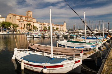 Port de p&ecirc;che c&ocirc;ti&egrave;re typique avec barques color&eacute;es align&eacute;es, &eacute;glise et phare en arri&egrave;re-plan. Port de La Ciotat et phare du B&eacute;rouard, M&eacute;diterran&eacute;e