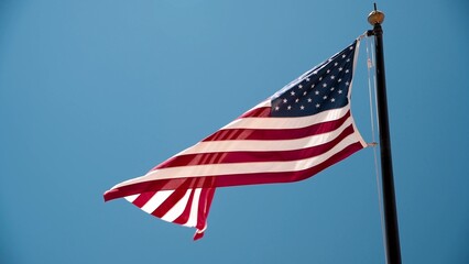 Obraz premium Beautiful american flag against the blue sky Slow motion