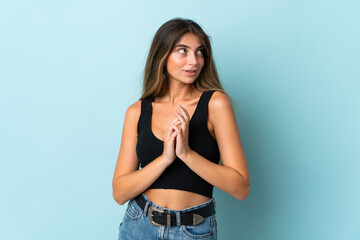 Young caucasian woman isolated on blue background scheming something