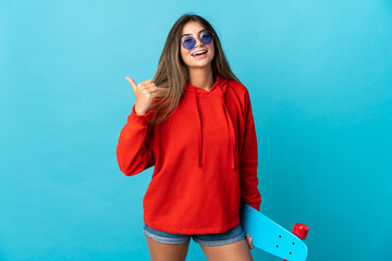 Young caucasian woman isolated on blue background with a skate and pointing to the side