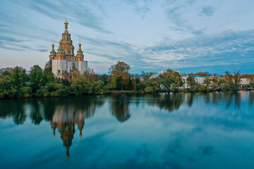 Olga's Pond and the Cathedral of Peter and Paul in Peterhof at sunset, the reflection of the sky and trees in the water, a church with domes, a photo for a postcard