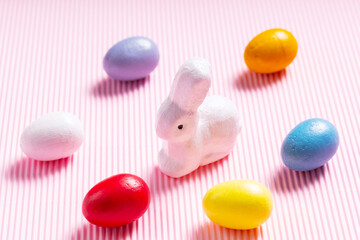 Easter eggs and white bunny. Easter decorations on a pink pastel background. Top view