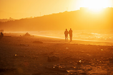 Relaxing young couple silhouette. Man and woman walking by a pathway on a beach.