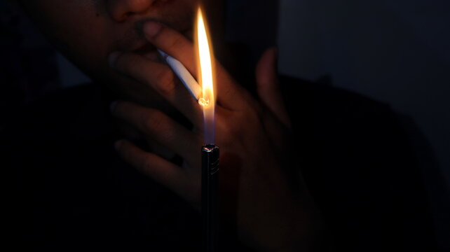 Smoker Lighting a Cigarette with a Gas Lighter. Close Up Shooting with a Person Smoking a Cigarette. light a cigarette with a gas lighter. photo in the dark.