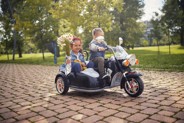  kids driving in electrical motorcycle toy in park