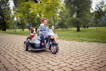  little girl driving electrical motorcycle toy with a sidecar with a dog in it