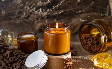 Scented candle in a glass jar. Coffee aroma. Star anise, cinnamon sticks, dried orange. Still life....