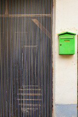 Green mailbox on the wall next to door