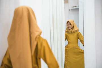 muslim kid trying dress in mirror in fitting room in shopping mall