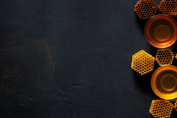 Honey with honeycomb on black table, top view. space for text