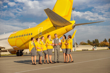 Airline workers standing near yellow aircraft at airfield