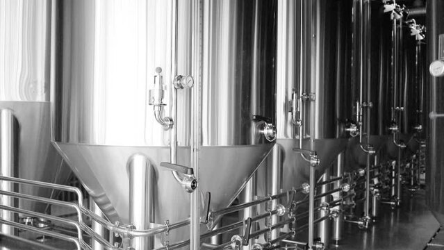 Craft beer production line in private microbrewery. Modern beer plant with brewering kettles, tubes and tanks made of stainless steel