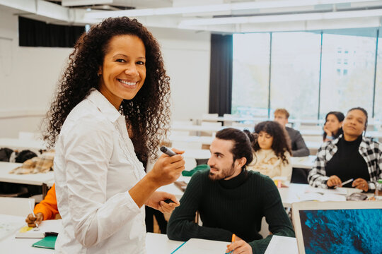 Portrait of smiling teacher with university students sitting in classroom