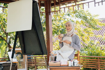 muslim Female artist painting on canvas drink tea
