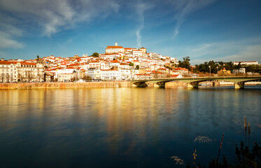 Fototapeta na wymiar Panorama of the city of Coimbra at the golden hour. View of the left bank of the Mondego River. 