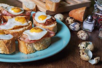 Slice of bread with bacon and grilled quail egg,on a wooden table.