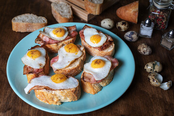 Slice of bread with bacon and grilled quail egg,on a wooden table.