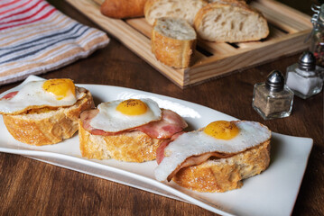 Slice of bread with bacon and grilled quail egg,on a wooden table.
