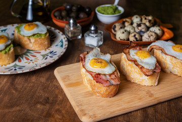 Slice of bread with bacon or avocado and grilled quail egg,on a wooden table.