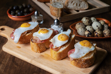 Slice of bread with bacon and grilled quail egg,on a wooden table.