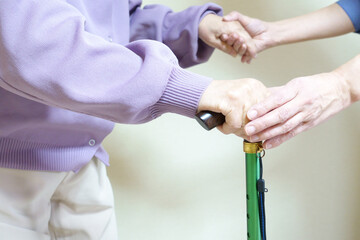 杖を突く高齢女性と、それを支える手　アップ