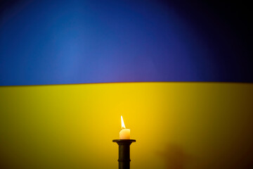 Frieden in der Ukraine. Kerze und die ukrainische Fahne im Hintergrund