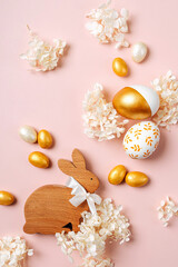 Easter Bunny and golden eggs with candy and flowers  on pastel pink background. Holiday concept. Happy Easter card.