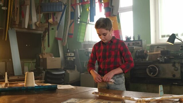 A boy in a plaid shirt makes a paper airplane