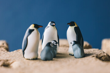 Cute miniature toy penguin colony. Wild animal family.