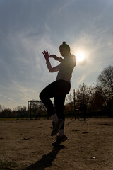 Silhouette of a girl exercising kickbox outside alone. Sunlight