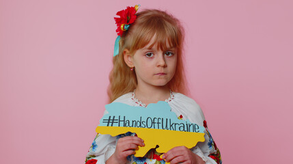 Sad toddler Ukrainian girl kid patriot in embroidery dress protesting war conflict raises banner with inscription massage text on map Hands Off Ukraine. Peace no war, stop aggression. Fight for rights