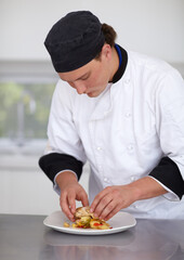 Creating a culinary masterpiece. Young chef preparing a chicken dish in a kitchen - Fine Dining.