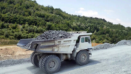 white Haul truck truck load of gravel rocks in the quarry from side view, big and large articulated dumping truck, dumper trailer, dump lorry. off-highway heavy-duty construction. - 489543348