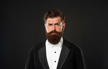 bearded man in tuxedo on black background, fashionist
