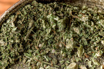 Close up macro shot of freshly ground recreational marijuana, in a silver grinder, ready to be used.  Details of trichomes and cannabis flower visible on drugs ready for use.