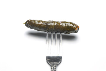 stuffed grape leaves on a fork on a white background. Stuffed collard greens with boiled leaves,...