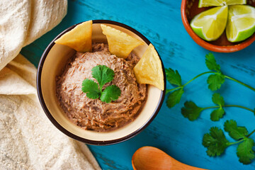青背景のメキシコのフリホーレス・レフリートス　トトポスをそえて　コピースペースあり Mexican Frijoles Refritos (Mexican Refried Beans) with Totopos on blue background with copy space